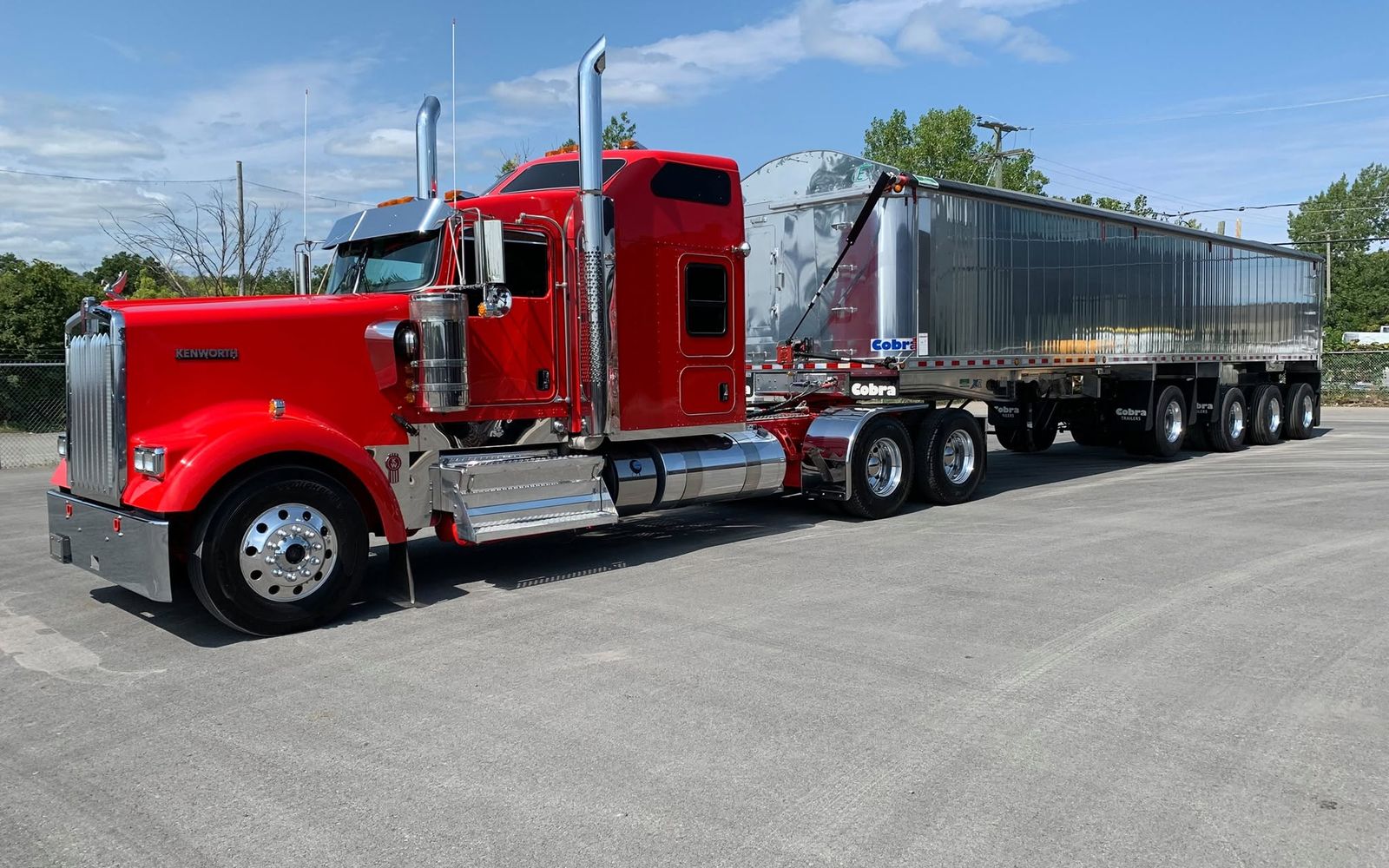 Camion Kenworth rouge et remorque à benne en aluminium dans une cour